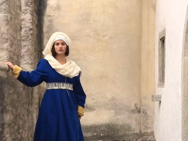 Eine Frau in spätmittelalterlicher Kleidung steht auf Schloss Lenzburg.