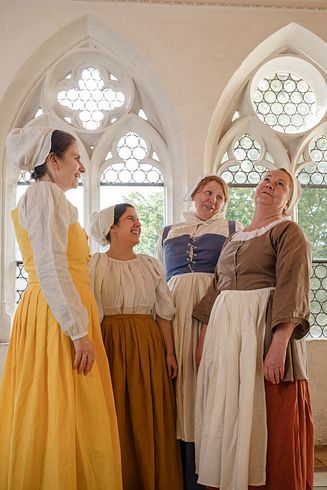 Vier Frauen, verkleidet als Klostermägde. Sie stehen singend im Kreuzgang des Klosters Wettingen.