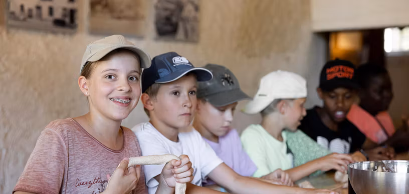 Kinder am Tisch sitzend, die Teig für Brot formen im Schloss Hallwyl