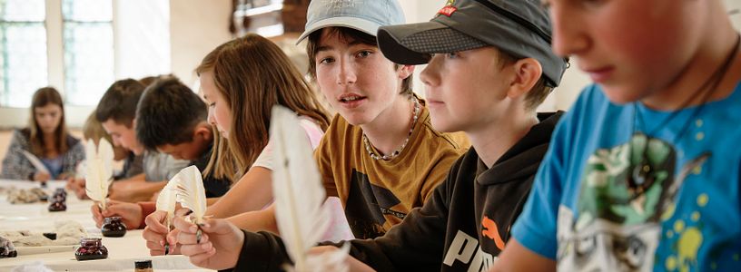 Eine Schulklasse beim Schreiben mit Tinte und Federkiel.