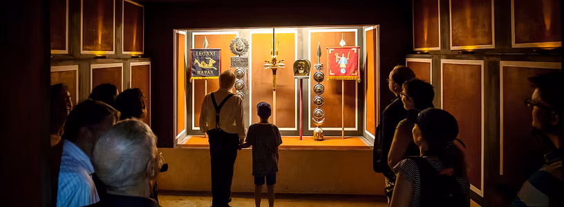 Besucher*innen betrachten im dunkeln das Fahnenheiligtum im Legionärspfad Vindonissa