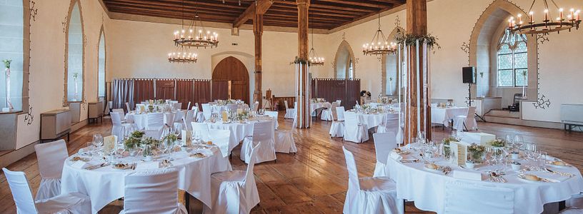 Urige Hochzeitslocation mit weiss gedeckten Tischen im Rittersaal Schloss Lenzburg 