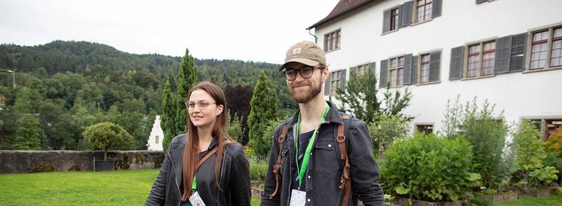 Eine Frau und ein Mann schreiten in Freizeitbekleidung durch den Garten der Klosterhalbinsel Wettingen (Foxtrail).