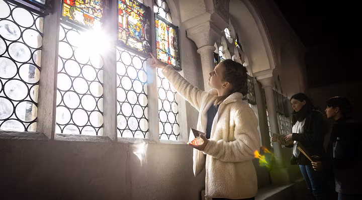 Mystische Stimmung im Kreuzgang des Klosters Wettingen. Ein Mädchen streckt im Gegenlicht der Sonne die Hand nach den Glasfenstern aus.