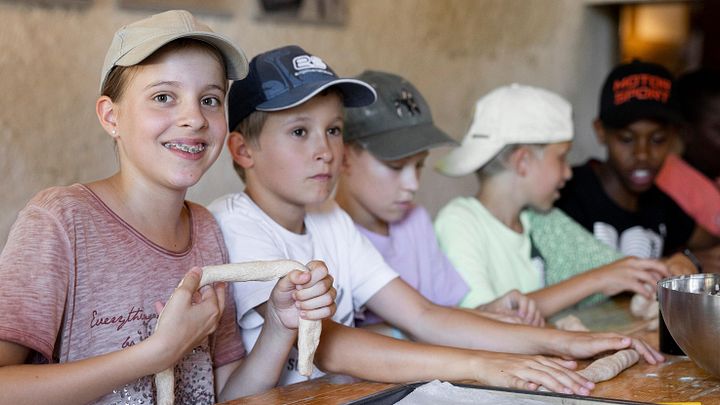 Kinder am Tisch sitzend, die Teig für Brot formen im Schloss Hallwyl