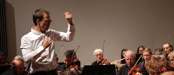 Dirigent steht vor Orchester