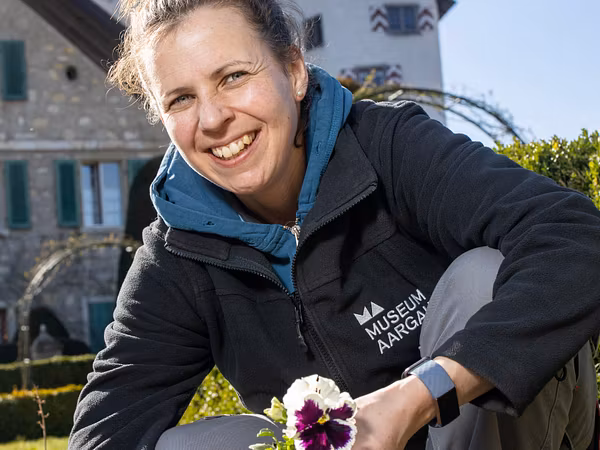 Gärtnerin Melissa Gögele im Rosengarten von Schloss Wildegg (im Hintergrund das Rebhaus und Schloss Wildegg)