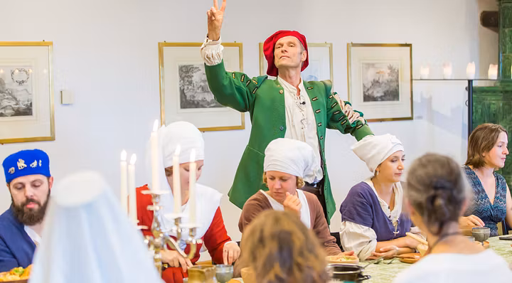 Verkleideter Museumsführer erzählt im Esstheater den dinierenden Gästen am Esstisch Anekdoten auf Schloss Habsburg