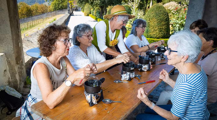 Workshop im Garten: Eine Gruppe Frauen setzt am Tisch und kocht Salbe; im Hintergrund der Garten von Schloss Wildegg