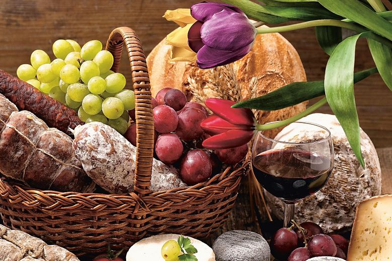 Korb gefüllt mit Trauben, Wurst und Käse und einer Tulpe
