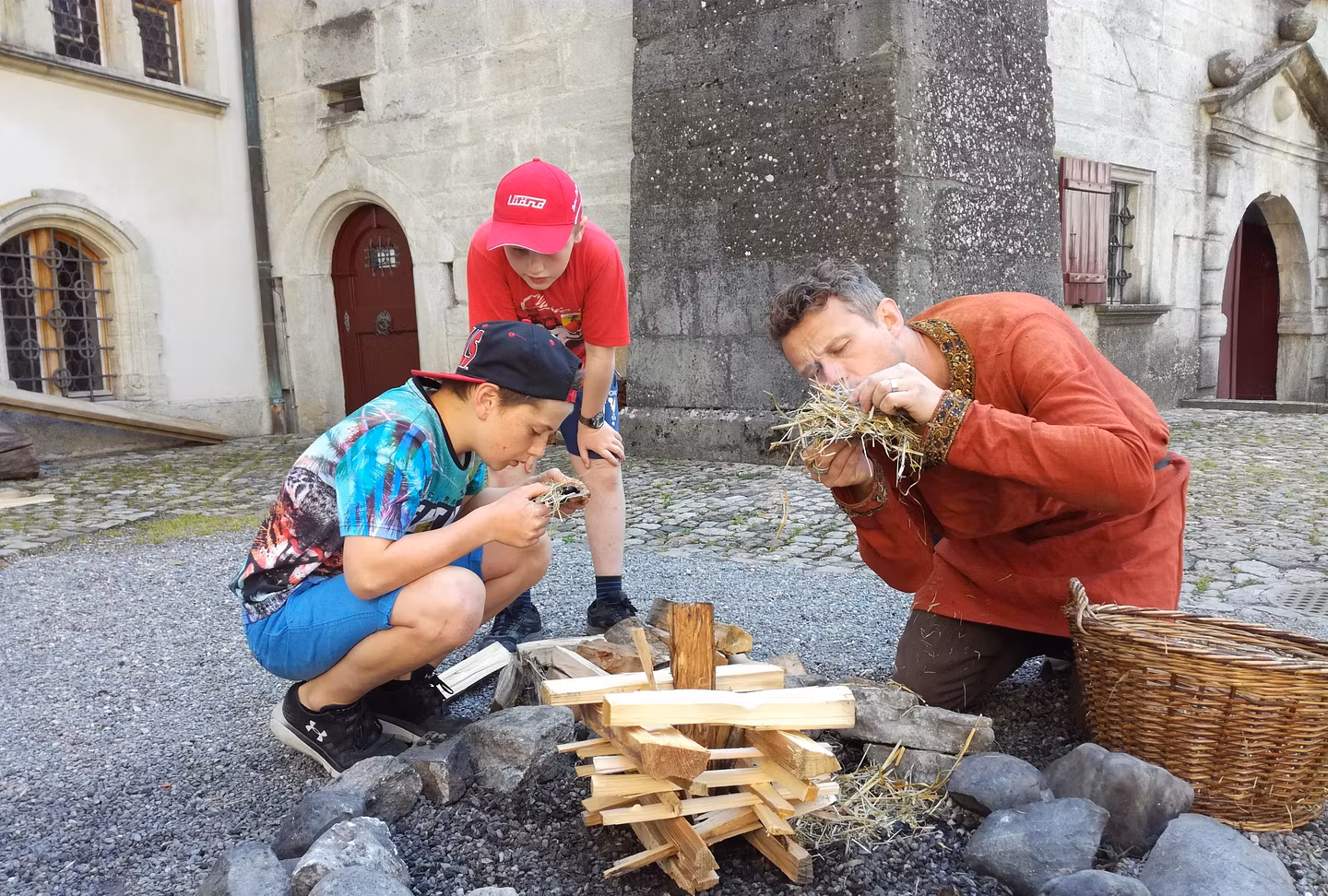 Kinder beim Workshop "Am Feuer" auf Schloss Lenzburg: Sie benutzen Stroh, um das Feuer zu entfachen. 