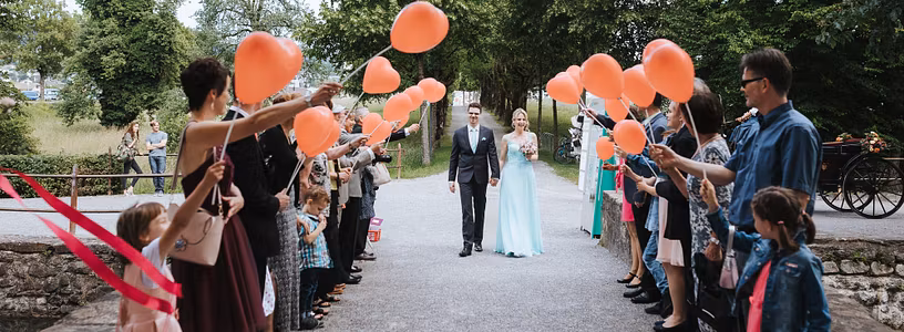 Ein Hochzeitspaar schreitet durch eine Festgesellschaft, die vor Schloss Hallwyl Spalier steht.