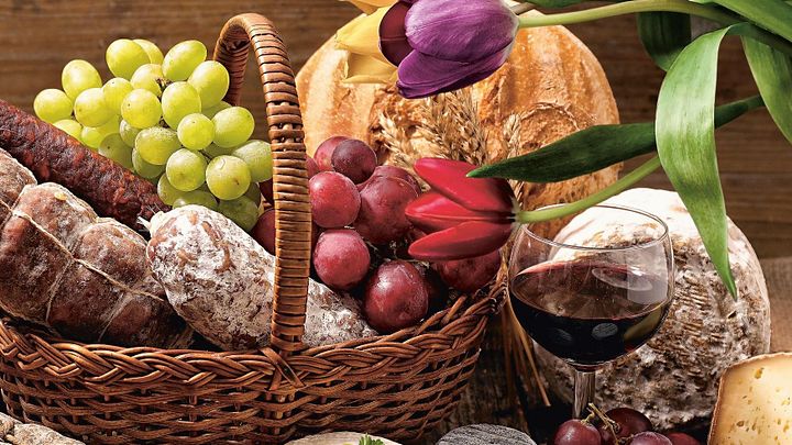 Korb gefüllt mit Trauben, Wurst und Käse und einer Tulpe