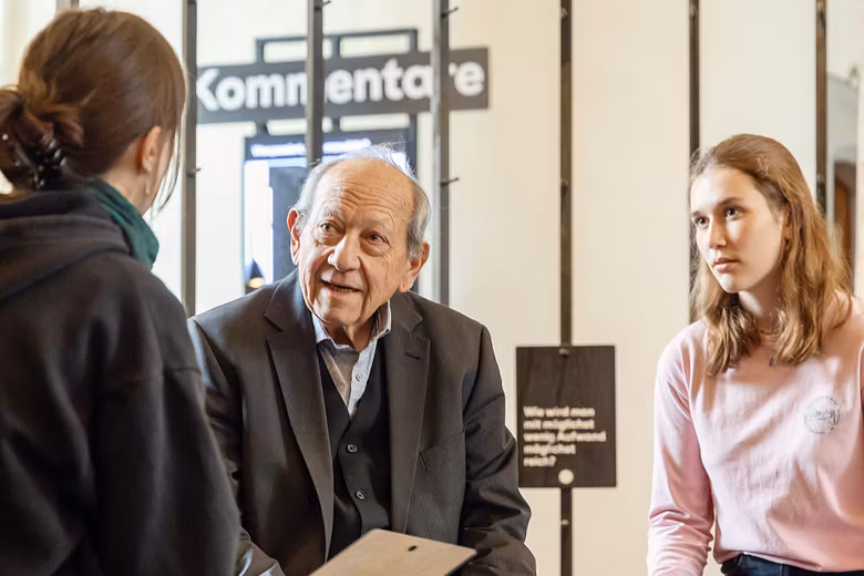 Ein älterer Mann im Gespräch mit zwei jugendlichen Frauen.