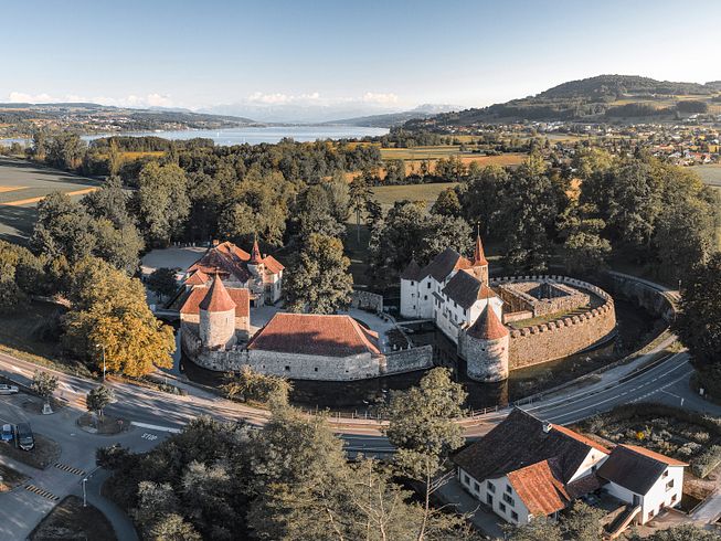 Luftaufnahme von Schloss Hallwyl mit Hallwilersee im Abendlicht