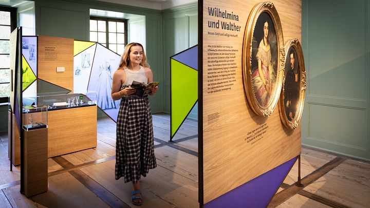 Eine Frau steht in einem Ausstellungraum mit bunten Wänden.