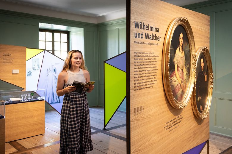 Eine Frau steht in einem Ausstellungraum mit bunten Wänden.