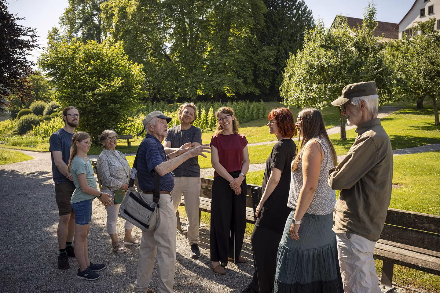 Besucherinnen und Besucher mit einem Museumsführer stehen im Park der Klostesrhalbinsel Wettingen