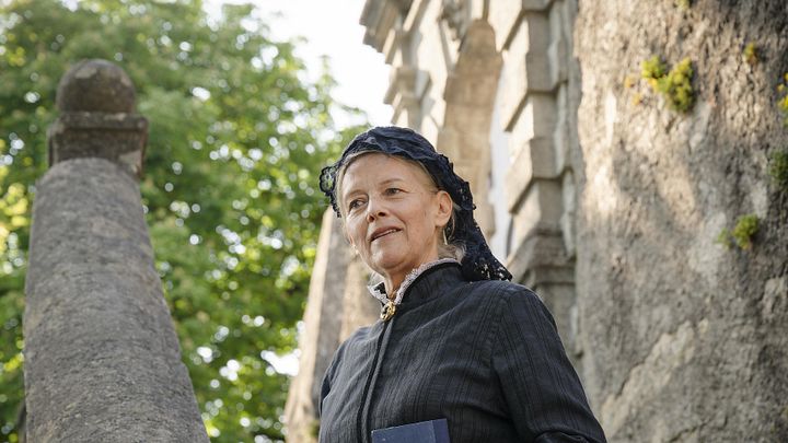 Eine Frau im Kostüm (als letzte Schlossherrin Julie von Effinger) steht auf einer Treppe im Aussenbereich von Schloss Wildegg